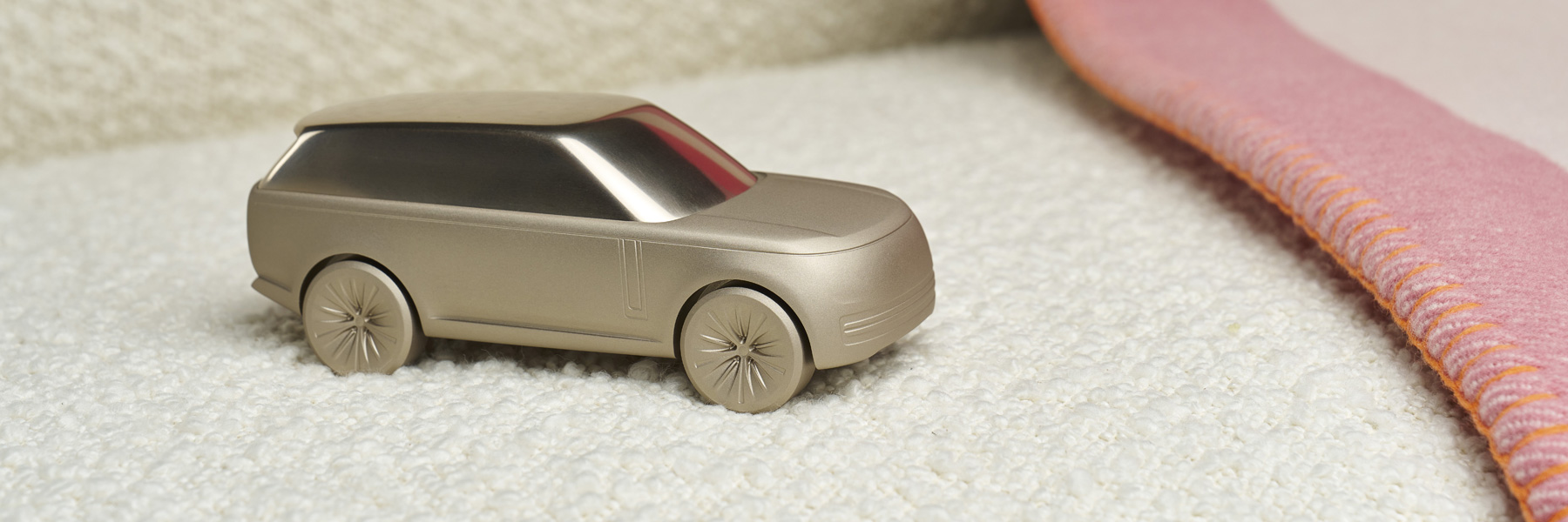 Range Rover London Collection - Category Banner. Product focus on Sunset Gold Sculpt model, edge of Cream Tea Blanket.